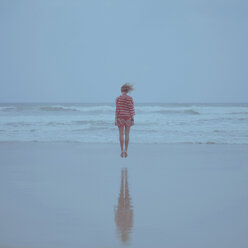 Rückansicht einer Frau, die am Strand gegen den blauen Himmel auf das Ufer springt - CAVF20377