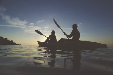 Silhouette friends kayaking on sea against sky during sunset - CAVF20378