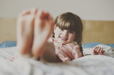 Portrait of cute girl lying on bed at home - CAVF20389