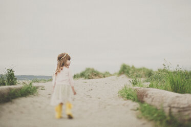 Rear view of girl walking footpath against clear sky - CAVF20391