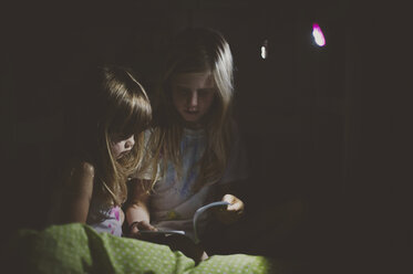 Mädchen lesen ein Buch in einem dunklen Raum zu Hause - CAVF20431