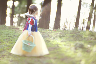 Side view of girl in dress carrying basket on field - CAVF20437