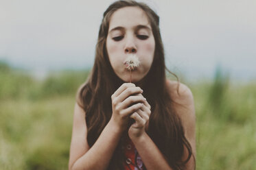 Cute girl blowing dandelion on field - CAVF20455