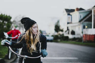 Mädchen schaut beim Radfahren auf der Straße weg - CAVF20469