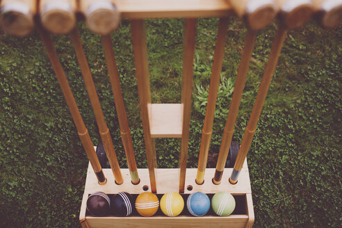 High angle view of croquet mallets and balls in holder on grass - CAVF20499