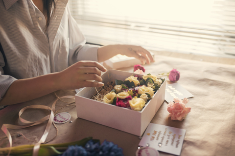 Mittelteil eines Blumenhändlers, der Blumen in einer Schachtel arrangiert, lizenzfreies Stockfoto