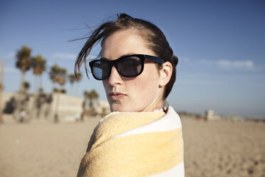 Porträt einer jungen Frau in ein Handtuch gewickelt am Strand - CAVF20544