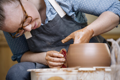 Close-up of woman molding shape on pottery wheel - CAVF20630