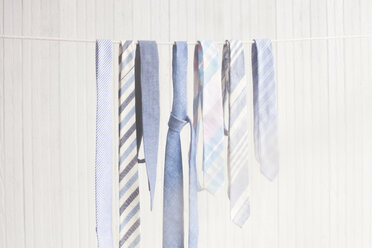 Krawatten hängen auf einer Wäscheleine an einer Holzwand - CAVF20720