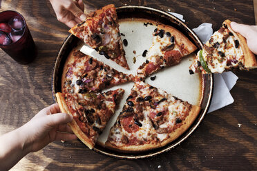 Overhead view of people eating pizza at wooden table - CAVF20728