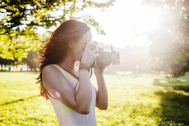 Seitenansicht einer Frau, die durch eine Kamera im Retro-Stil fotografiert - CAVF20777