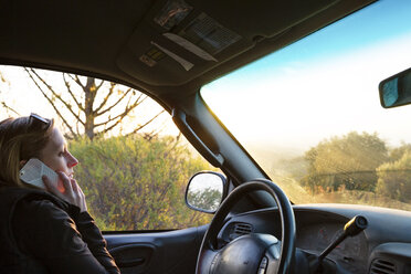 Side view of woman talking on phone while sitting in car - CAVF20793