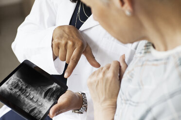 Midsection of doctor showing X-ray image to patient in hospital - CAVF21051