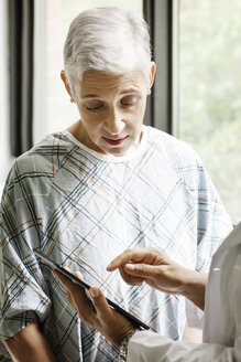 Ausgeschnittenes Bild eines Arztes, der einem Patienten einen medizinischen Bericht auf einem digitalen Tablet in einer Klinik zeigt - CAVF21053