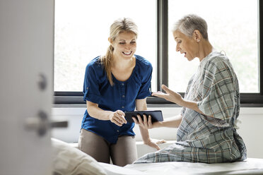 Glückliche Mutter zeigt ihrer Tochter einen medizinischen Bericht auf einem digitalen Tablet im Krankenhaus - CAVF21055