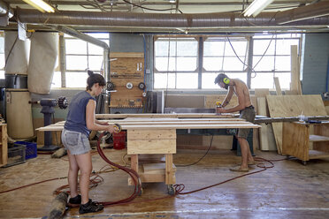 Schreiner in voller Länge beim Schleifen von Holzbrettern in der Werkstatt - CAVF21102