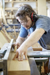 Carpenter wearing ear protection while working in carpentry workshop - CAVF21111