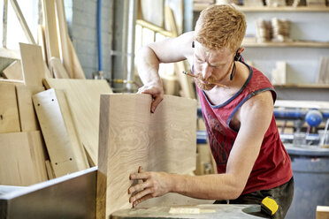 Carpenter holding pencil in mouth while working in workshop - CAVF21114