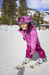Glückliches Mädchen beim Skifahren auf verschneitem Feld - CAVF21948