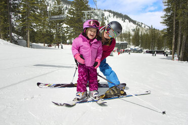 Mother and daughter skiing on snow covered field - CAVF21950