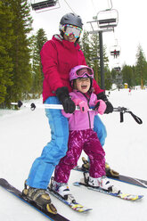 Glückliche Mutter und Mädchen beim Skifahren auf einem schneebedeckten Feld - CAVF21951