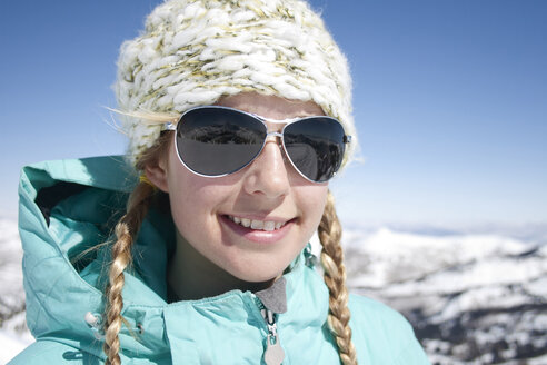 Lächelnde junge Frau mit Sonnenbrille vor einem Berg stehend - CAVF21957