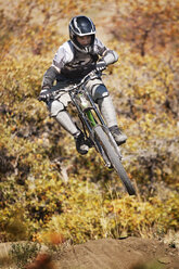 Man mountain biking against trees - CAVF21975