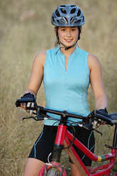 Portrait of smiling woman with bicycle on field - CAVF21976