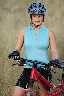 Porträt einer lächelnden Frau mit Fahrrad auf einem Feld - CAVF21976