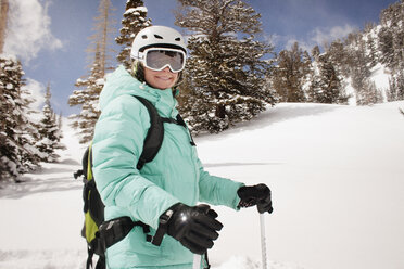 Glückliche Frau beim Skifahren auf einem schneebedeckten Berg vor Bäumen - CAVF22002