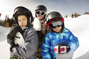 Lächelnde Geschwister mit Snowboards auf einem schneebedeckten Feld - CAVF22020