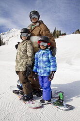 Vater und Sohn stehen auf Snowboards auf einem verschneiten Berg - CAVF22023