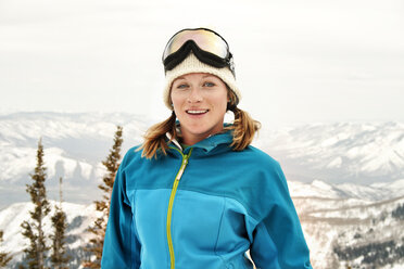 Porträt einer lächelnden Frau, die vor schneebedeckten Bergen steht - CAVF22027