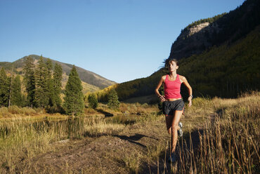 Woman jogging on lakeshore - CAVF22033