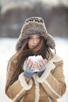Portrait of beautiful woman wearing warm clothing while holding snow - CAVF22080