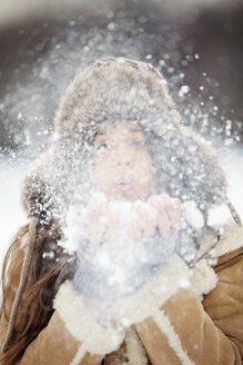 Close-up of woman wearing warm clothing while blowing snow - CAVF22081