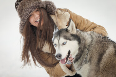 Porträt einer glücklichen Frau mit Siberian Husky im Winter - CAVF22082