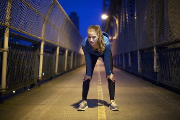 Portrait of tired young woman bending on illuminated bridge at night - CAVF22107