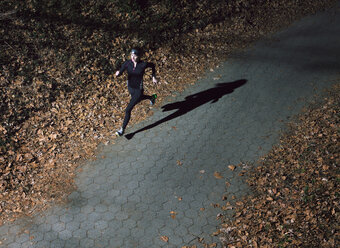 Hohe Winkelansicht einer jungen Frau, die nachts auf einem beleuchteten Fußweg läuft - CAVF22121