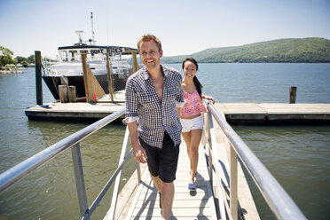 Friends walking on jetty by yacht over lake against sky - CAVF22216