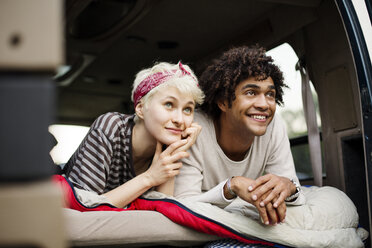 Smiling couple lying in back of camping van - CAVF22227