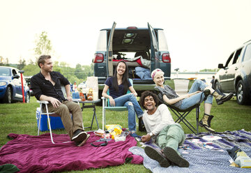 Glückliche Freunde genießen auf dem Campingplatz gegen den klaren Himmel - CAVF22230