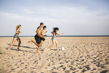 Freunde spielen Fußball auf Sand am Strand gegen den Himmel - CAVF22313