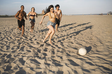 Glückliche Freunde spielen Fußball am Strand an einem sonnigen Tag - CAVF22314