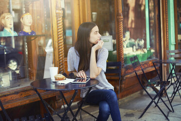 Thoughtful woman sitting by table at sidewalk cafe on sunny day - CAVF22343