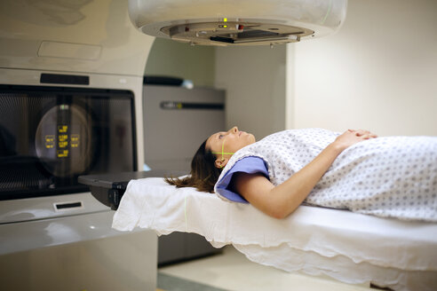 Weibliche Patientin liegt unter einem Röntgengerät im Krankenhaus - CAVF22357