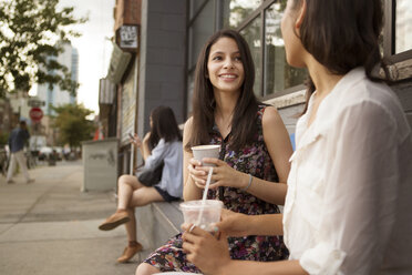 Smiling friends having coffee while sitting outside cafe - CAVF22370