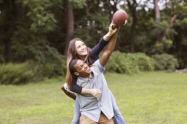 Mann nimmt Frau beim Fußballspielen auf dem Feld huckepack - CAVF22436
