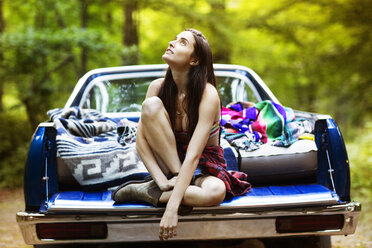 Thoughtful woman sitting in pick-up truck at forest - CAVF22466