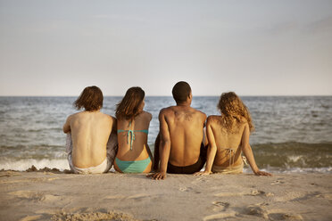 Rückansicht von am Strand sitzenden Freunden gegen den Himmel - CAVF22488